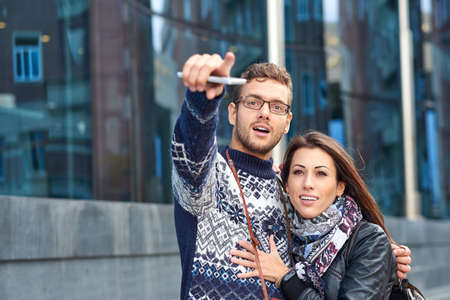 two happy tourists couple searching location together with a phone and map and pointing with the...