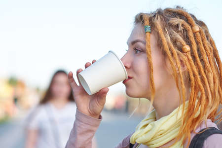 Portrait teenager woman with dreadlocks drinking coffee in paper cupの写真素材