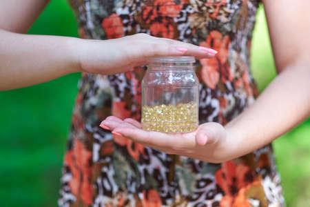 hand holding daily supplements, vitamins or medication on green background