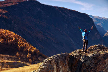 Hiker woman with backpack on rock of a mountain and enjoying sunrise. Travel Lifestyle success concept adventure active vacations outdoor mountaineering sportの写真素材