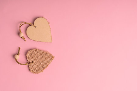 Top view of two wooden heart shaped decoration laying on pink background with copy space. Concept of love and relationship using for valentine's day holidayの写真素材