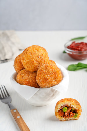 Homemade Arancini Sicilian rice balls or croquettes deep fried and stuffed with minced beef meat in...