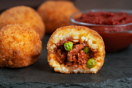 Close up view of whole and sliced arancini sicilian or italian rice balls deep fried and stuffed...
