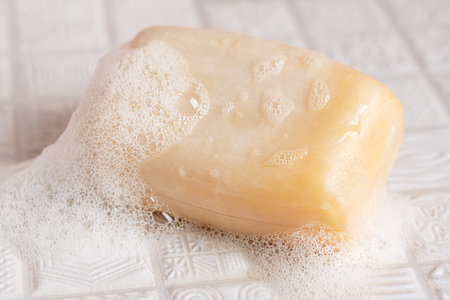 Close up view of organic aromatic antibacterial wet natural square soap bar with foam and bubbles on...