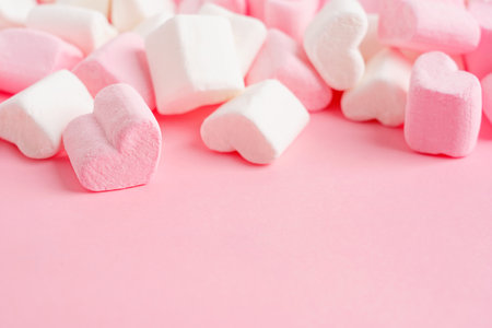 Closeup view of bunch of sweet homemade heart shape marshmallow soft jelly dessert snack made of sugar and gelatin on pink background with copy space used for greetingの写真素材