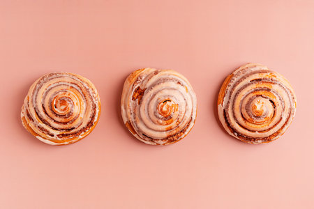 Top view of three delicious homemade sweet cinnamon rolls bun dessert glazed with sugar icing laying...