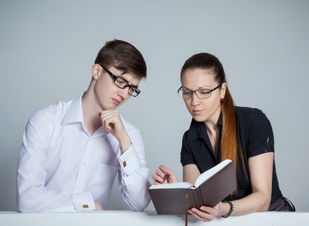 Beautiful businesswoman discussing schedule with bored clerkの写真素材