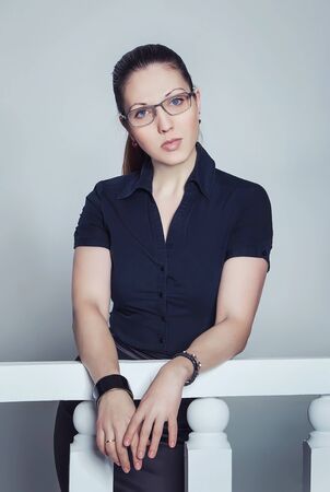 Portrait of beautiful young businesswoman in black blouse leaning on a banisterの写真素材