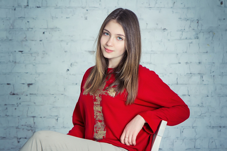 Portrait of beautiful teen girl sitting on a chairの写真素材
