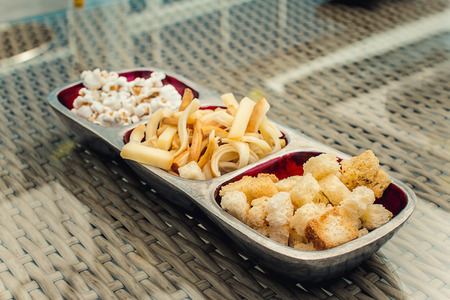 Different sorts of snacks for beer on the table of summer caffee. Cheese popcorn and bread crackersの写真素材
