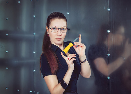 Serious attractive businesswoman wearing glasses holding screwdriverの写真素材