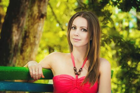 Portrait of young smiling happy woman sitting on the bench in a parkの写真素材