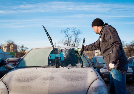 Man scraping frozen  front windshield of his carの写真素材