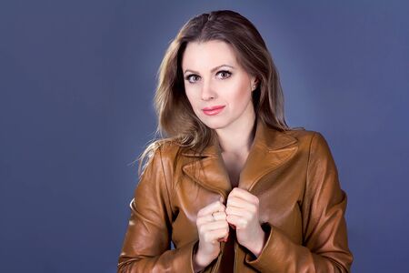 portrait of  beautiful young self-confident smiling woman in brown leather jacketの写真素材