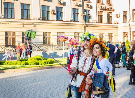 Zaporizhia/Ukraine- May 19, 2016: girls in colorful flower wreaths taking photo on phone using selfy stick on celebration of national Ukrainian embroidered clothes, known as Vyshyvanka  Dayのeditorial素材