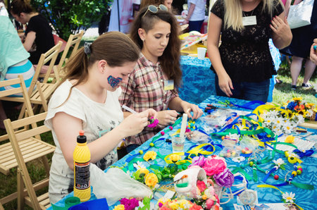 Zaporizhia/Ukraine- June 5, 2016: teen girls making wreaths and bracelets using artificial flowers, colorful ribbons and beads at handicraft workshop on charity family festival organized in regions with most quantity of refugees from Donetsk area, occasioのeditorial素材