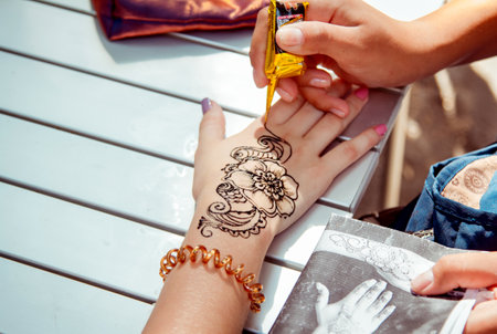 Zaporizhia/Ukraine- September  3, 2016: Charity festival for children â City of professions . Applying temporary henna tattoo activity.  Closeup teen girl arm - flower ornament painting process.のeditorial素材