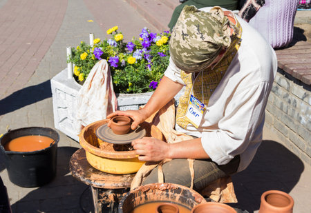 Zaporizhia/Ukraine- September  17, 2016: Family festival of homemade pickled canned vegetables and preserves. Outdoors pottery workshop.  Potter presenting  process of ceramic jug creation on a turning wheel.のeditorial素材