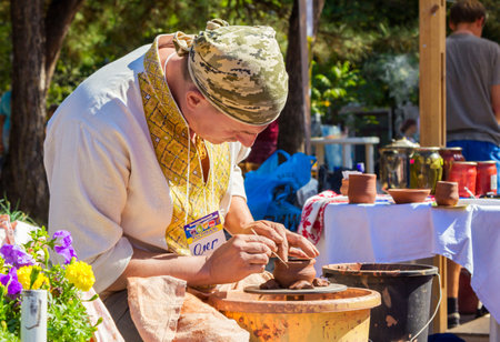 Zaporizhia/Ukraine- September  17, 2016: Family festival of homemade pickled canned vegetables and preserves. Outdoors pottery workshop.  Closeup hands of potter, presenting  process of ceramic jug creating on a turning wheel.のeditorial素材