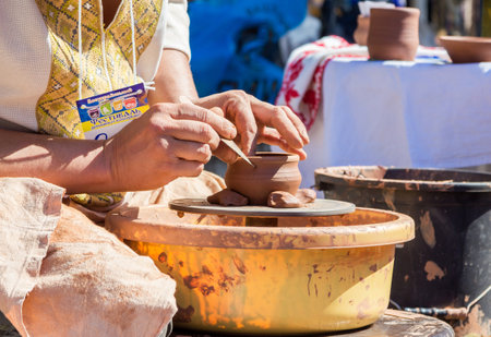 Zaporizhia/Ukraine- September  17, 2016: Family festival of homemade pickled canned vegetables and preserves. Outdoors pottery workshop.  Closeup hands of potter, presenting  process of ceramic jug creating on a turning wheel.のeditorial素材