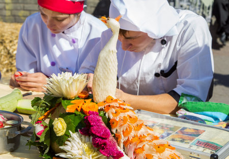 Zaporizhia/Ukraine- September  17, 2016: Family festival of homemade pickled canned vegetables and preserves. Peacock figure carved from zucchini decorated by carrot elements. Culinary school students participating at vegetables carving workshopのeditorial素材