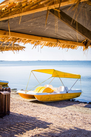 Yellow pedal catamaran boat with tent on a sea coast on a sunny dayの写真素材