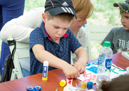 Zaporizhia / Ukraine- May 28, 2017: Charity Family Festival: art and craft activity, boy cocentrated on work at drawing workshop outdoorsのeditorial素材