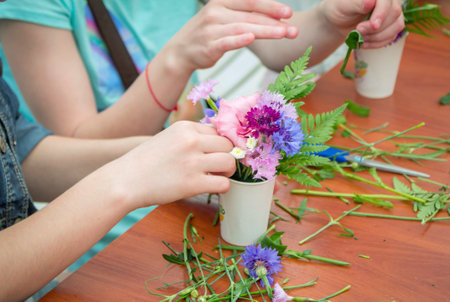 Zaporizhia / Ukraine- May 28, 2017: Charity Family Festival: closeup hands of girl, participating at floristic workshop, learning to arrange fresh flowers in beautiful bouquetsのeditorial素材