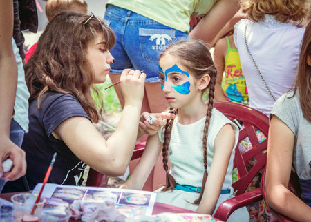 Zaporizhia / Ukraine- May 28, 2017: Charity Family. Girl getting abstract blue watercolor mask painted on her face.のeditorial素材