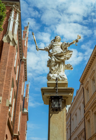 Krakow / Poland - August 15, 2017: symbol of justice stone statue - woman figure, holding golden arrows and scepter - near Faculty of law building, part of Jagiellonian Universityのeditorial素材