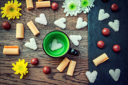 Sweets - chocolate candies and heart shape cookies with coconut chips and flowers on a wooden table and black stone tray.の写真素材
