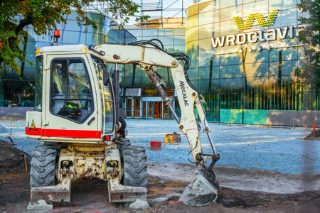 Wroclaw / Poland - August 20, 2018: view of excavator on new Wroclaw bus station construction. Glass facade of modern building.のeditorial素材
