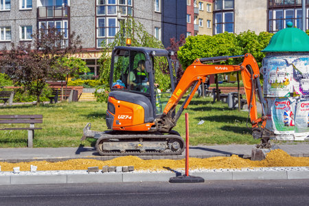 Katowice / Poland- May 1, 2018: bicycle lane construction. Small orange and black crawler excavator...
