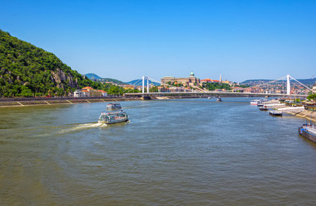 Budapest/Hungary- May 6, 2018: spring cityscape with Danube River, bridge and touristic boats, Gellert Hill, green trees and blue skyのeditorial素材