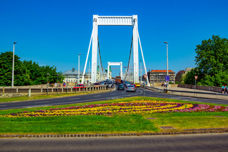 Budapest/Hungary- May 6, 2018: spring view of the city -  bridge and road with moving cars, colorful lawn with flowers and grass, walking people. Green trees and blue sky.のeditorial素材