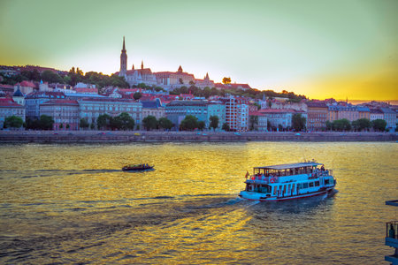 Budapest/Hungary- May 6, 2018: evening cityscape with Danube River, beautiful historic buildings and towers, touristic boats, colorful sunset sky and Buda Castle on horizon.のeditorial素材