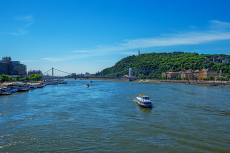 Budapest/Hungary- May 7, 2018: spring cityscape - Gellert hill with Citadella and Liberty Statue, Danube River, colorful historic buildings, bridge, touristic boats, green trees and blue skyのeditorial素材