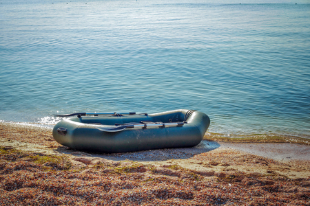 Tranquil landscape with calm sea water, sandy shore and inflatable rubber fisher boat, sunny summer day.の写真素材