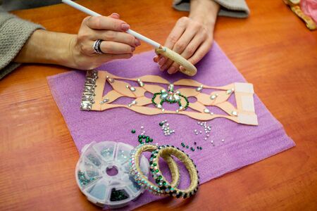 Close-up of woman`s hands, decorating bracelets with colorful shiny rhinestones, Handicraft process concept.の写真素材