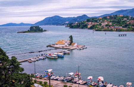Corfu Island/Greece- May 4, 2019: view of Vlacherna Monestery on a small island of Kanoni Peninsula at Kerkyra, boats on blue sea water surface and mountains on the horizon.のeditorial素材
