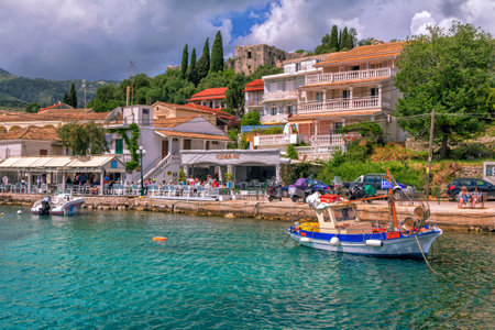 Corfu Island / Greece- May 6, 2019: view of beautiful Kassiopi village - colorful houses, street caf?, sea lagoon with calm turquoise water, white boats, blue sky and mountains on the horizon.のeditorial素材