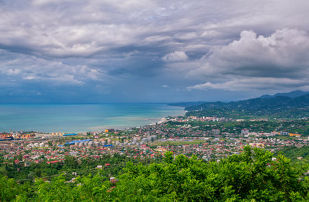 Batumi / Georgia - July 12, 2019: summer aerial cityscape of Black sea resort - colorful buildings and houses, green trees, mountains and cloudy sky.のeditorial素材