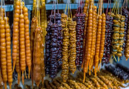 Colorful traditional homemade Georgian sweet dessert- churchkhela, made of fruit juice and nuts, hanging at outdoor market for sale.の写真素材