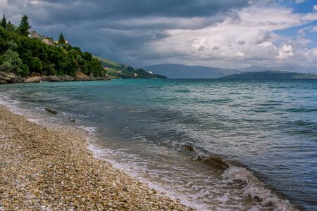 Beautiful landscape - turquoise colored sea water, golden sand, gray sky with dark stormy clouds and...