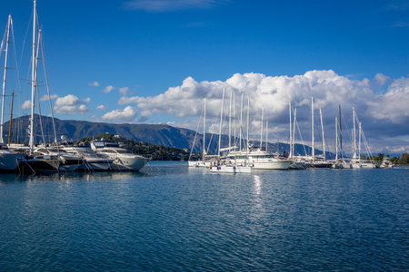 Corfu Island / Greece- May 5, 2019: View of beautiful Gouvia port marina - calm sea, white yachts and blue sky with white clouds, reflecting on water surface, and mountains on the horizon.のeditorial素材