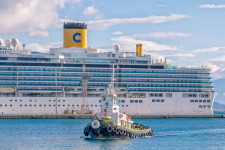 Corfu Island / Greece- May 7, 2019: small tow boat moving along the sea with large white cruise liner on background.のeditorial素材