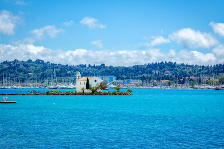 Corfu Island/Greece- May 5, 2019: View of beautiful Gouvia Bay, ancient Ypapanti church â small white house on a pier, resort village and mountains on the horizon. Summer landscape.のeditorial素材
