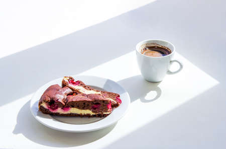 Cup of coffee and homemade brownie cake with cottage cheese and cherries on the table. Sunny morning...