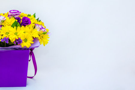 Part view of beautiful bright colorful bouquet with yellow chrysanthemum and purple eustoma flowers in a box on white background.の写真素材
