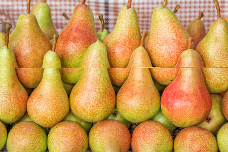 Ripe red and yellow pears for sale at farm outdoor market. Summer fruits harvest.